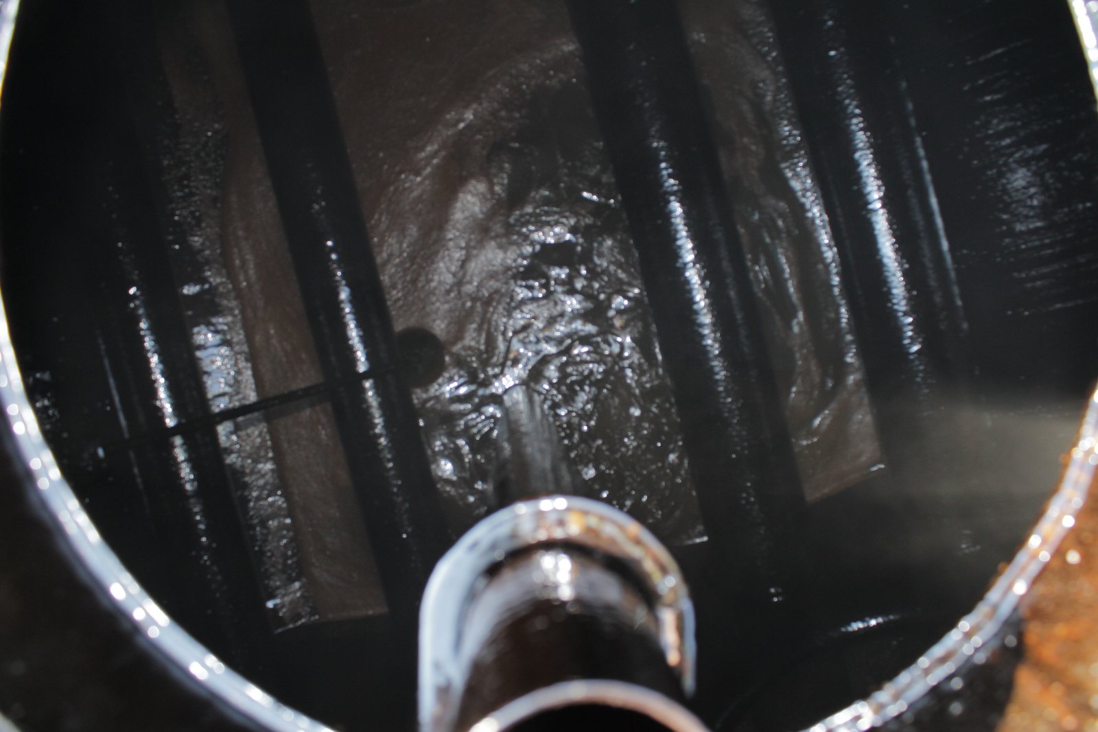 Separated and solidified asphalt inside a distributor tank before cleaning